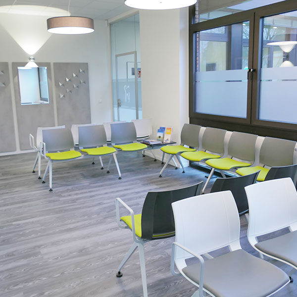 Wartebereich für Patienten der Praxis. Die Stühle sind in U-Form und haben einen grünen Bezug.